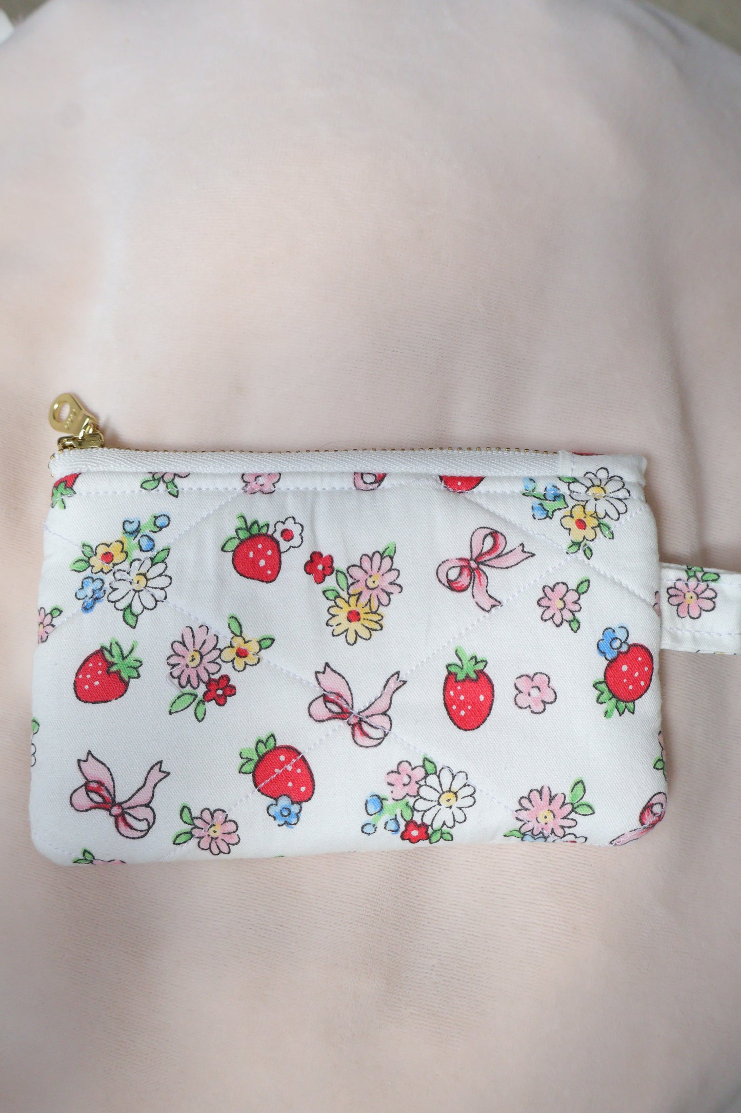 Small pouch with floral and strawberry pattern on a plain background