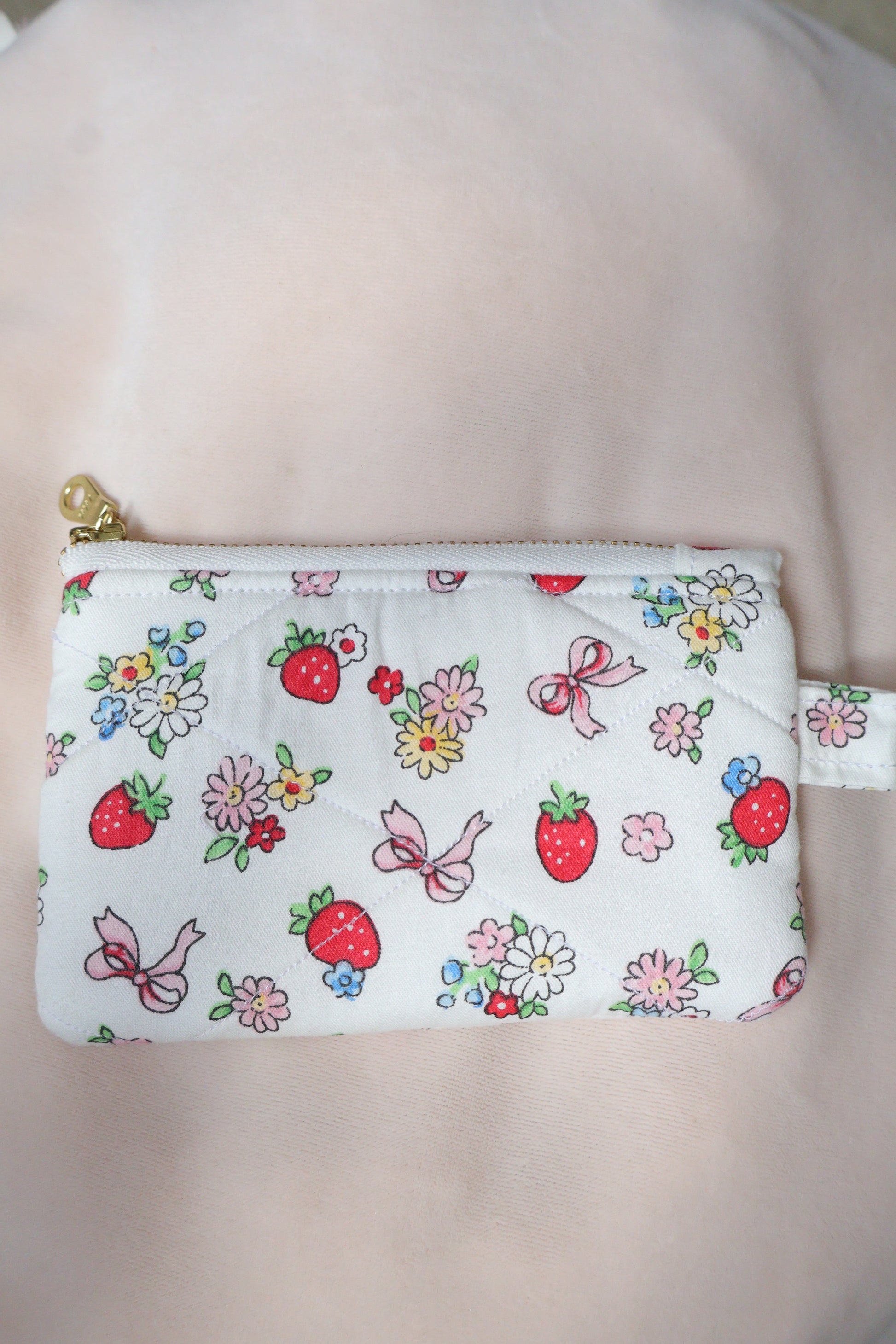 Small pouch with floral and strawberry pattern on a plain background