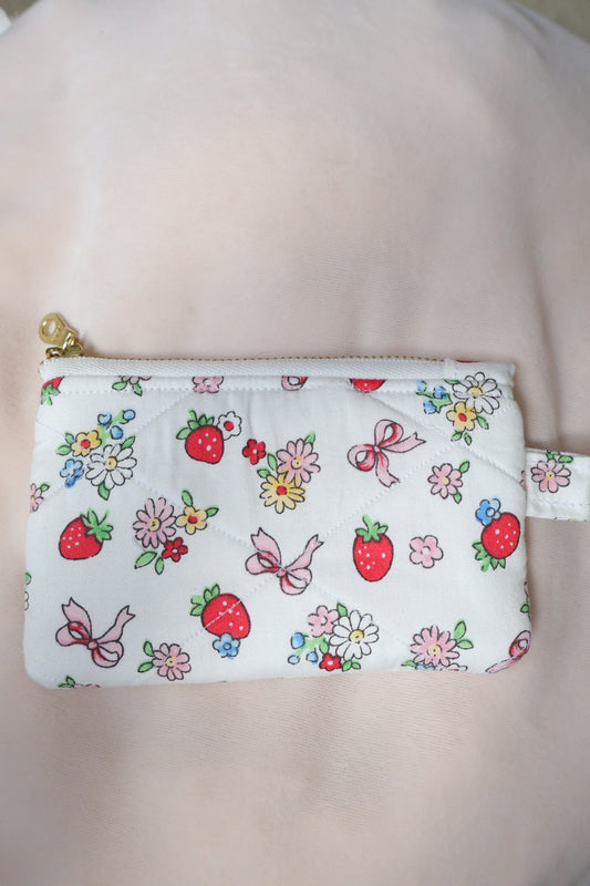 Small pouch with floral and strawberry pattern on a plain background